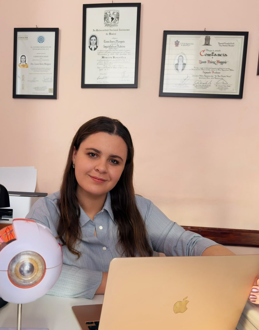 Dra. Laura Sáenz, oftalmóloga, en su consultorio con sus certificaciones y un modelo anatómico del ojo